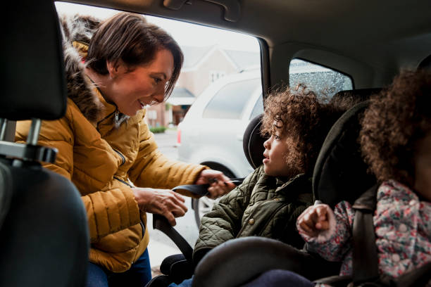 Putting Child Into Car Seat A mother is fastening her young child into a car seat northern europe family car stock pictures, royalty-free photos & images
