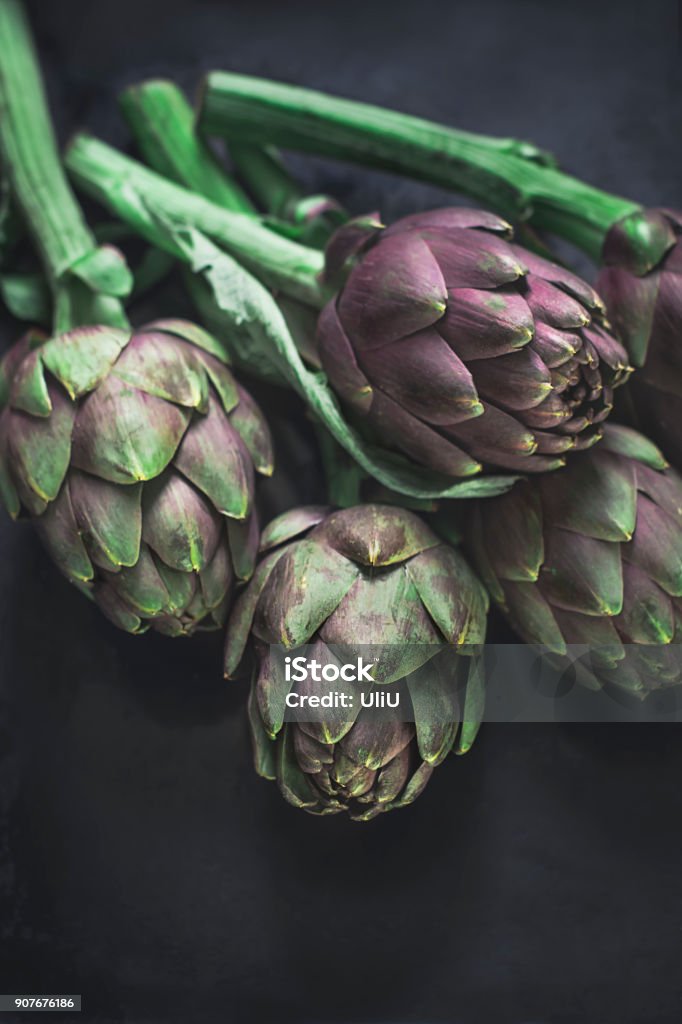 Roman fresh artichokes on a dark background Roman artichokes with texture on a dark background. Ingredients of southern Italian cuisine. Vertical format Agriculture Stock Photo