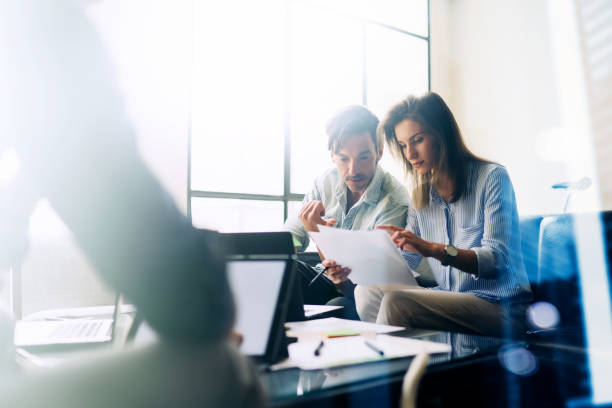 istock Teamwork concept.Young business people working with new startup project.Mobile devices on table,documents and marketing reports.Blurred background,visual effect,flare.Horizontal. 907676666