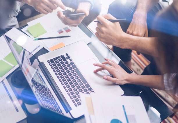 istock Closeup view of working process.Business people making new startup project at office.Analyze document, plans.Modern laptop on wood table, papers, documents.Horizontal,cropped. 907686584