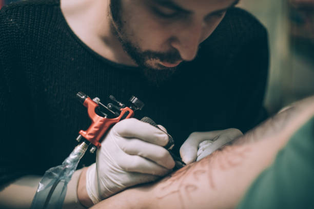 istock Artist tattooing arm 907687586