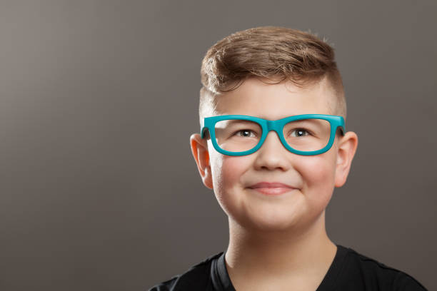 istock Smiling teenager boy with eyeglasses on grey background 907689974