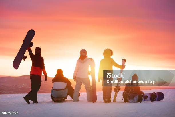 Happy Friends At Ski Resort Against Sunset Stock Photo - Download Image Now - Skiing, Ski, Friendship