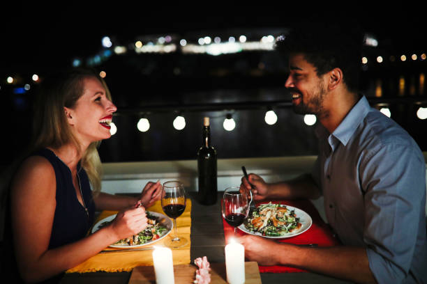Young beautiful couple having romantic dinner on rooftop Young beautiful couple in love having romantic dinner at night on rooftop candle light dinner stock pictures, royalty-free photos & images
