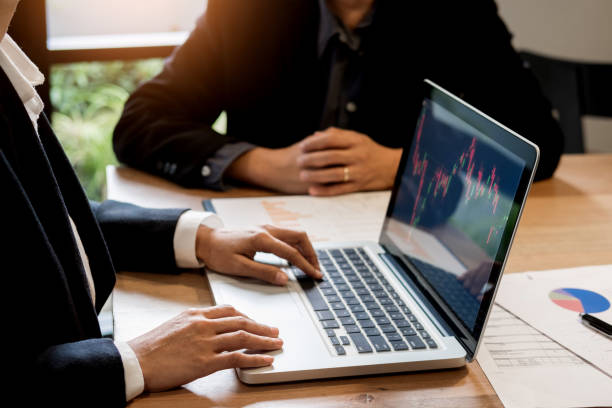 istock Midsection Of Business People Using Laptop At Table 907698474