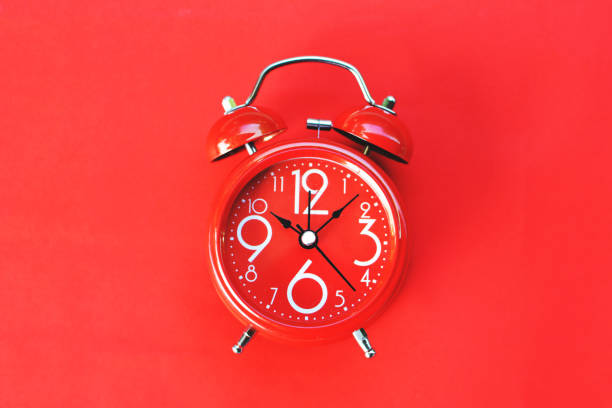 istock Close-Up Of Alarm Clock On Red Background 907698804