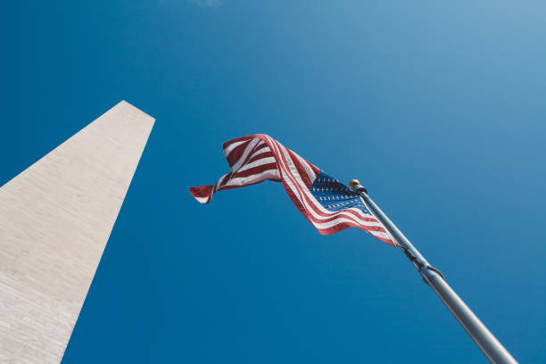 istock Low Angle View Of American Flag Fluttering Against Clear Blue Sky 907699030