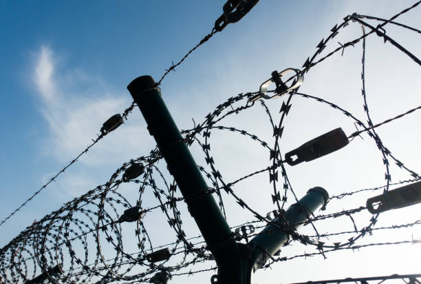istock Low Angle View Of Razor Wire Fence Against Sky 907700188