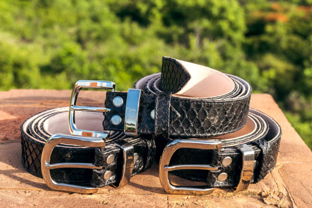 istock Fashion luxury snakeskin leather belts outdoors. Python belts on a tropical background 907724546