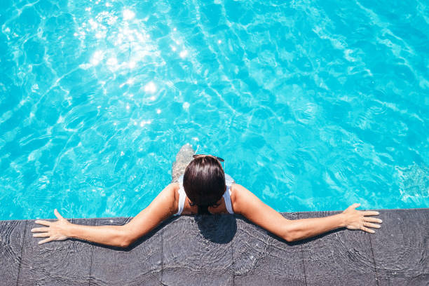 istock Woman enjoy the sun in swimming pool 907729736