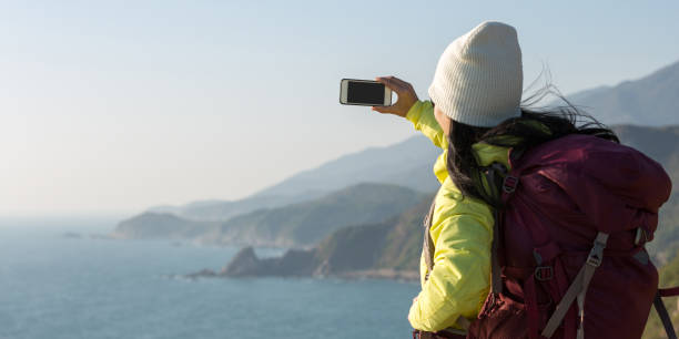 istock Young Woman Hiker Using Smartphone taking photo at Seaside 907737466