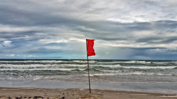 istock Red flag on the beach. 907745756