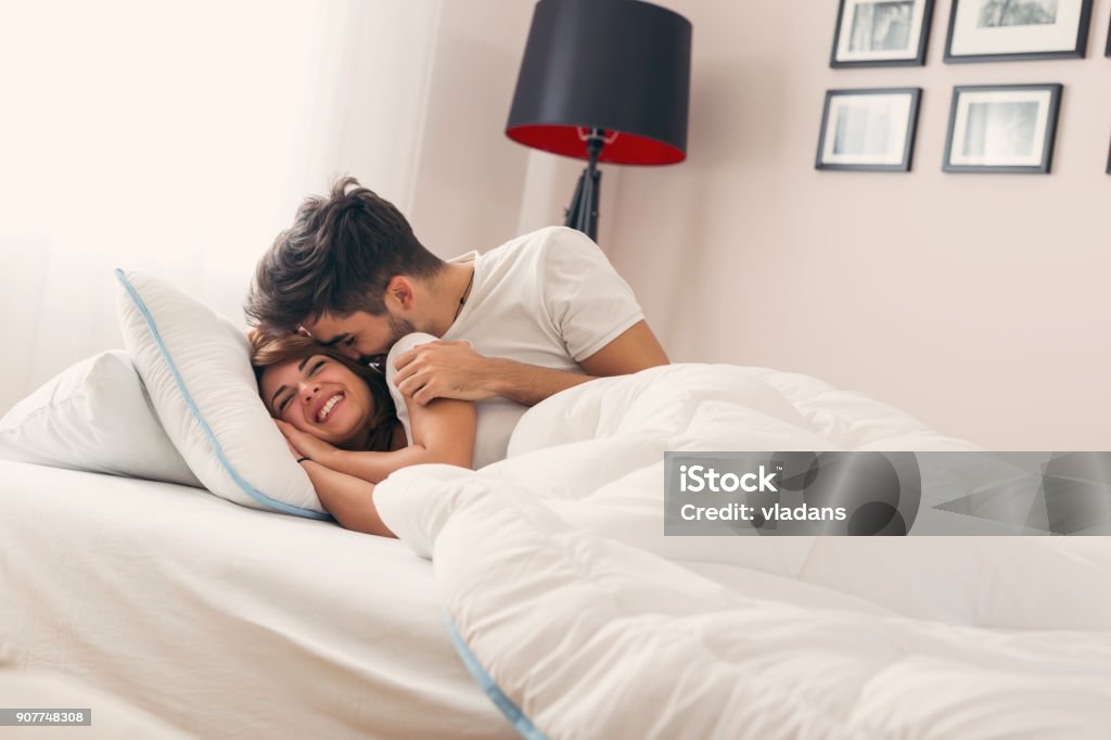 Waking up Couple in love lying in bed, hugging and kissing after waking up in the morning Bed - Furniture Stock Photo