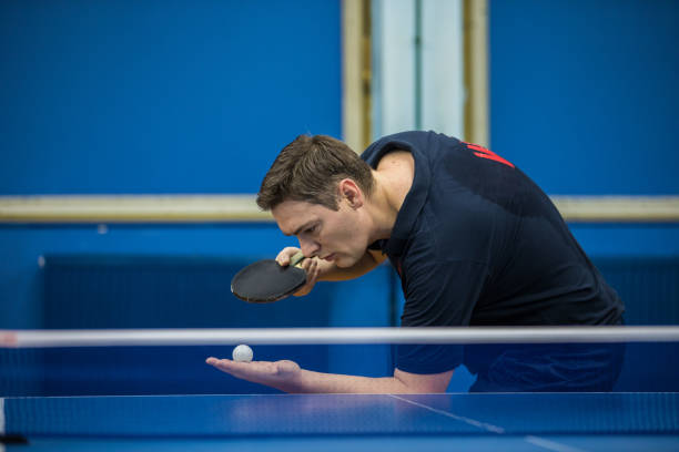 Concentrated mid adult man playing table tennis indoors