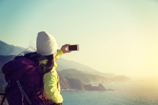 istock Young Woman Hiker Using Smartphone taking photo at Seaside 907751320