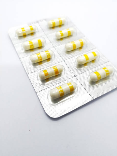 Medication concept. Celecoxib is a nonsteroidal anti-inflammatory drug used to treat pain or inflammation, white-yellow capsules are in silver blister. Sealective focus, Isolated on white background and copy space. concepto de medicamento. celecoxib es un medicamento antiinflamatorio no esteroide utilizado para tratar el dolor o la inflamación, blanco-amarillo cápsulas en blister plateado. sealective enfoque, aislados en fondo blanco, espacio de copia.