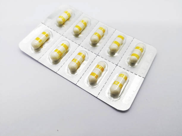 Medication concept. Celecoxib is a nonsteroidal anti-inflammatory drug used to treat pain or inflammation, white-yellow capsules are in silver blister. Sealective focus, Isolated on white background and copy space. concepto de medicamento. celecoxib es un medicamento antiinflamatorio no esteroide utilizado para tratar el dolor o la inflamación, blanco-amarillo cápsulas en blister plateado. sealective enfoque, aislados en fondo blanco, espacio de copia.