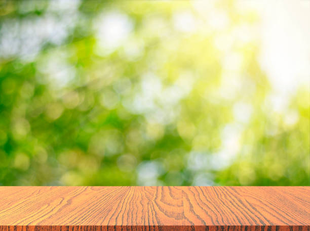 istock Wooden tabletop with fresh green nature blurred background 907753402