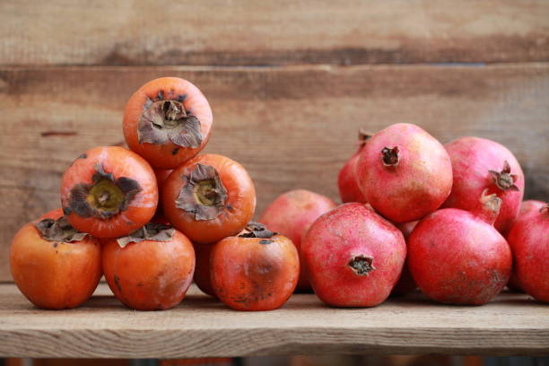 istock persimmon and pomegranates on a wooden table 907759018