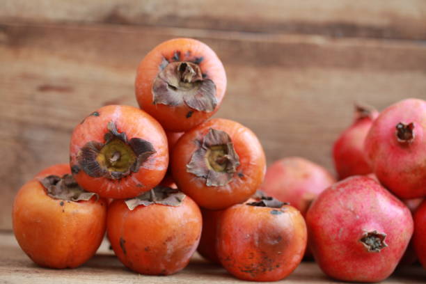 istock persimmon and pomegranates on a wooden table 907759024