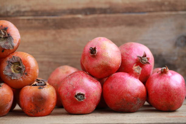 istock persimmon and pomegranates on a wooden table 907759064
