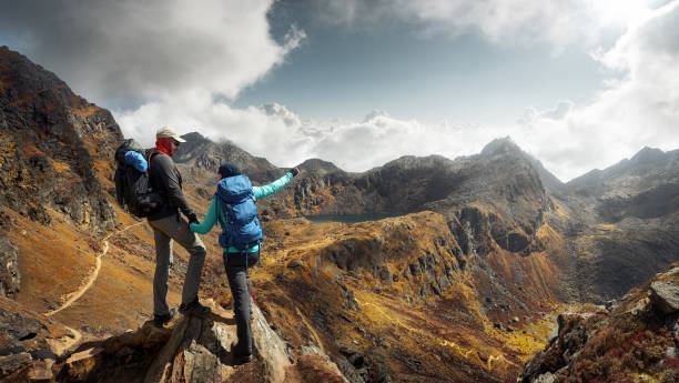 istock Two Hikers with backpacks in mountains enjoying panoramic on view of mountains 907761074