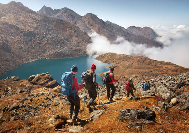 Group tourists with Backpacks descends down on Mountain Trail during Hike. Group of tourists with backpacks descends down mountain trail to lake during a hike in the national park Lantang, Nepal. nepal stock pictures, royalty-free photos & images