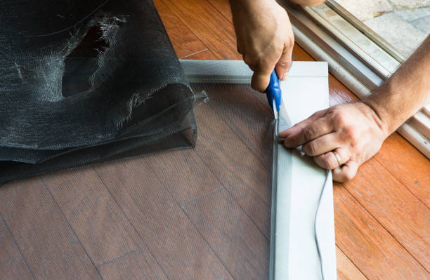 Man replacing ripped old patio door screen stock photo