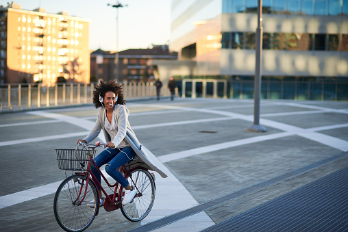 Horizontal photo of an African American woman with bike listening to music