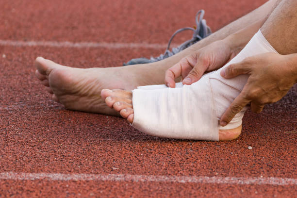Male athlete applying compression bandage onto ankle injury