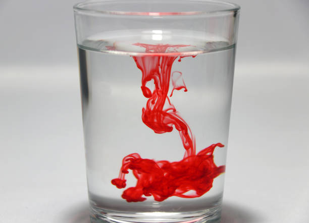 Red color drop on the water in the glass with white background. stock photo