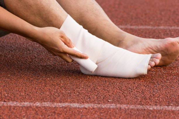 istock Male athlete applying compression bandage onto ankle injury 907782462