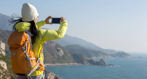 istock Young Woman Hiker Using Smartphone taking photo at Seaside 907791912