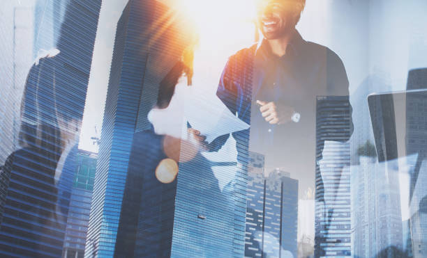 istock Teamwork concept process.Young team of coworkers making great business discussion in modern coworking office.Double exposure,skyscraper building blurred background.Horizontal.Flares effect. 907793120