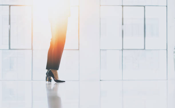 istock Businesswoman standing at sunny loft office front of panoramic windows.Blurred background.Horizontal.Flares effect. 907805470