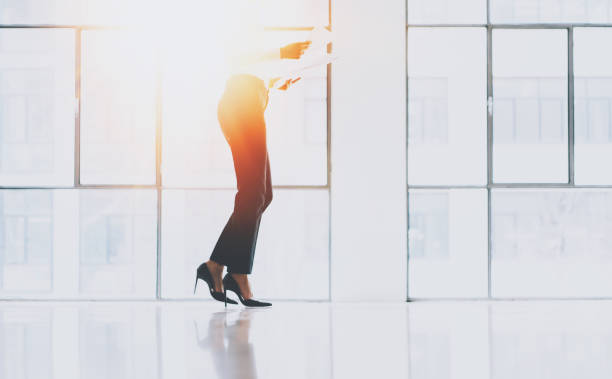 istock Businesswoman holding paper documents in hands at sunny loft office.Panoramic windows on blurred background.Horizontal.Flares. 907805514