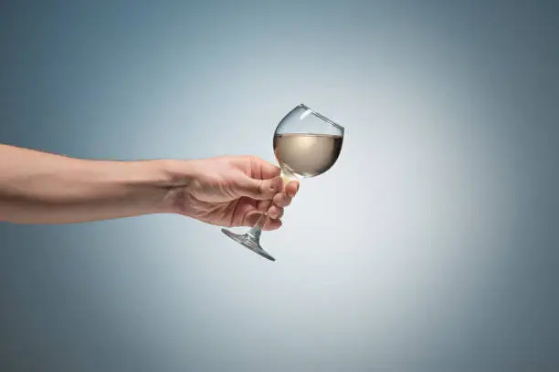 Close-up view of white wine glass in male hand