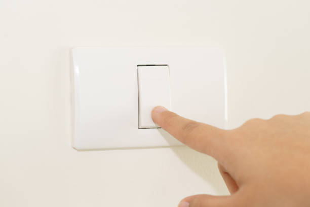 istock Close up of finger turning off on light switch on wall 907810394