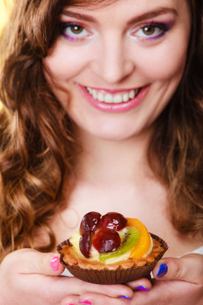 istock Smiling cute woman holds fruit cake in hand 907811398