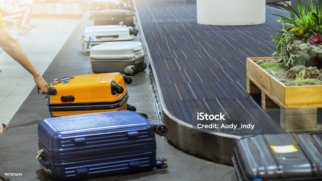 suit case on luggage conveyor belt at baggage claim in airport terminal. Checked Pattern Stock Photo