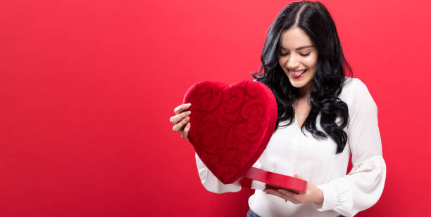 istock Happy young woman holding a big heart gift box 907811698