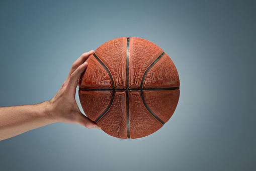 Low key shot of a hand holding a basket ball at studio