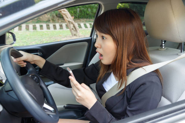 istock Shocked woman watching video or text to someone with smart phone while driving fast a car distracted. 907816748