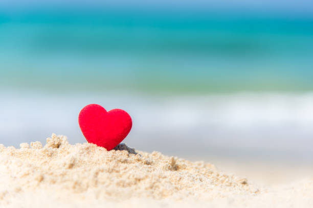 istock Valentine Concept.  Red hearts on the sand summer beach. 907819384