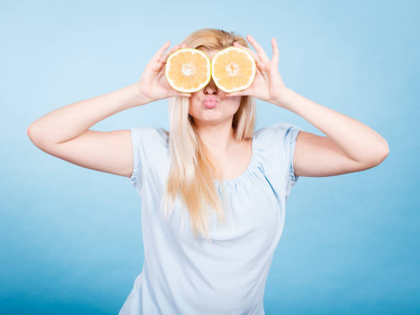 istock Girl covering her eyes with grapefruits 907819484