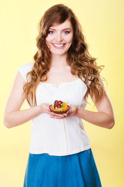 istock Smiling cute woman holds fruit cake in hand 907825506