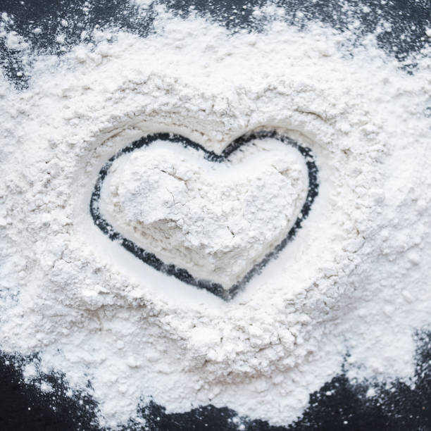 istock Valentine Day Concept idea image - Heart shape in a baking flour on black background. Cooking love recipe concept 907825994