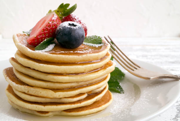 istock American pancakes with berries on a light background. 907831152