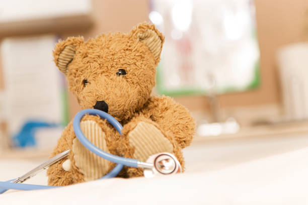 Brown teddy bear and stethoscope on exam table in pediatrician doctor's office.