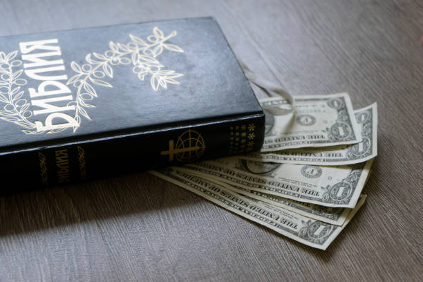 istock Cyrillic Holy bible with money dollars 907834990
